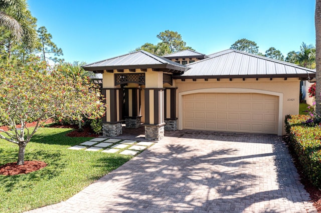 view of front facade featuring a garage, decorative driveway, metal roof, and stucco siding