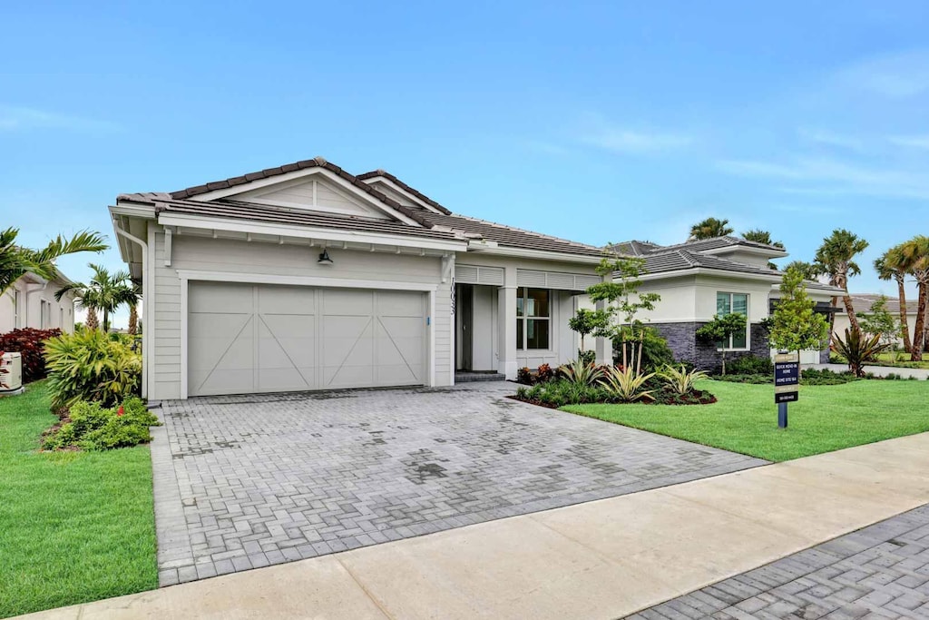 10033 Driftwood Way, Palm Beach Gardens, FL 33412 - single story home with a garage, decorative driveway, a front yard, and a tile roof
