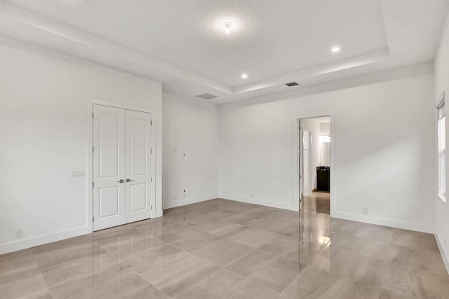 unfurnished room with recessed lighting, a raised ceiling, visible vents, and baseboards