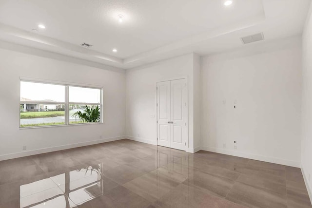 unfurnished room featuring baseboards, visible vents, a tray ceiling, and recessed lighting