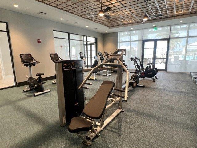 exercise room with french doors, a raised ceiling, visible vents, and baseboards