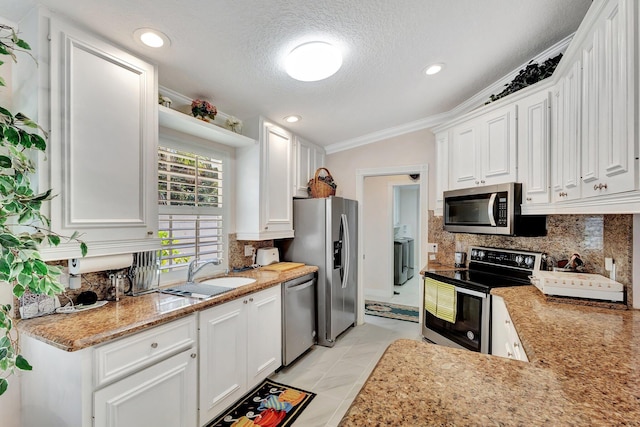 kitchen featuring stainless steel appliances, decorative backsplash, ornamental molding, white cabinets, and a sink