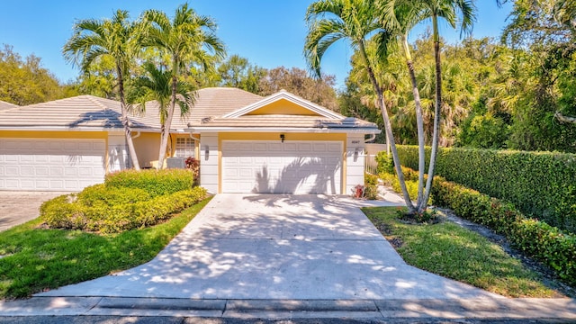 ranch-style house featuring driveway, an attached garage, a tiled roof, and stucco siding