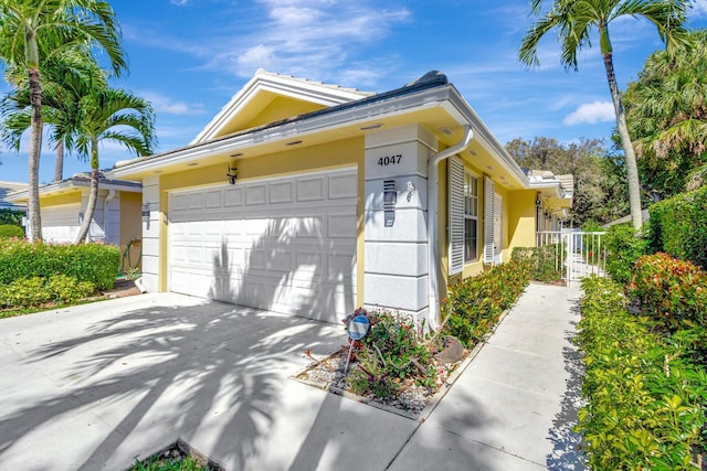 4047 Grove Point Rd, Palm Beach Gardens, FL 33410 - view of property exterior featuring stucco siding, an attached garage, and concrete driveway