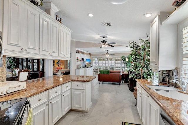 kitchen with black range with electric cooktop, a sink, visible vents, and white cabinetry