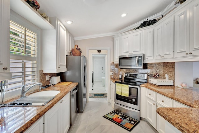 kitchen featuring appliances with stainless steel finishes, white cabinetry, ornamental molding, and backsplash