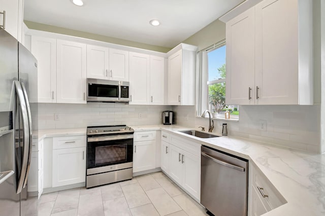 kitchen featuring stainless steel appliances, white cabinets, a sink, and tasteful backsplash