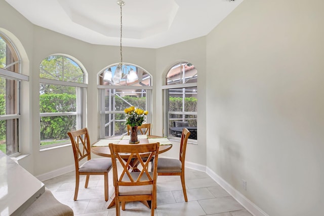 dining area featuring a raised ceiling, a notable chandelier, baseboards, and light tile patterned floors