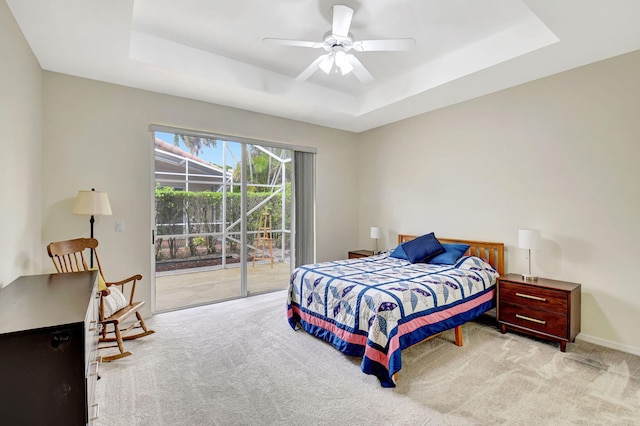 bedroom featuring access to exterior, a raised ceiling, light colored carpet, and ceiling fan