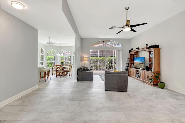 living room with a wealth of natural light, a ceiling fan, and baseboards