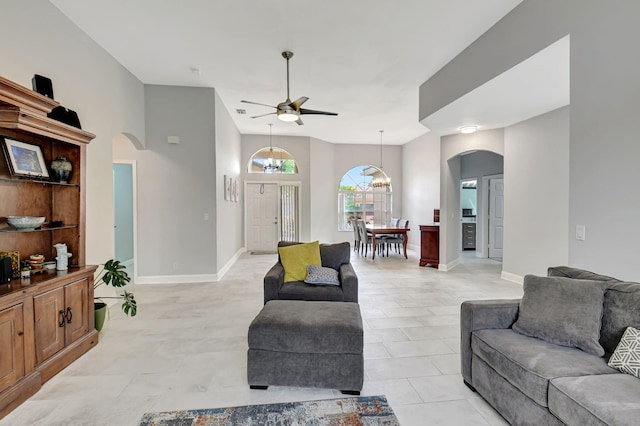 living room with baseboards, arched walkways, and ceiling fan with notable chandelier