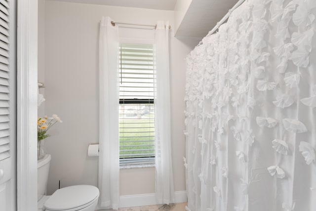 bathroom with a shower with curtain, toilet, and baseboards