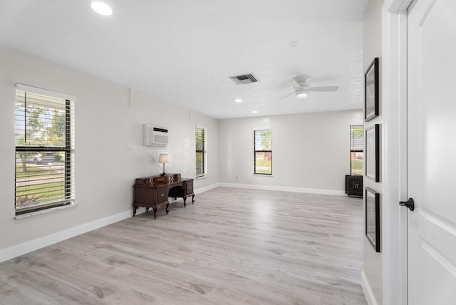 living area featuring light wood-type flooring, visible vents, an AC wall unit, recessed lighting, and baseboards