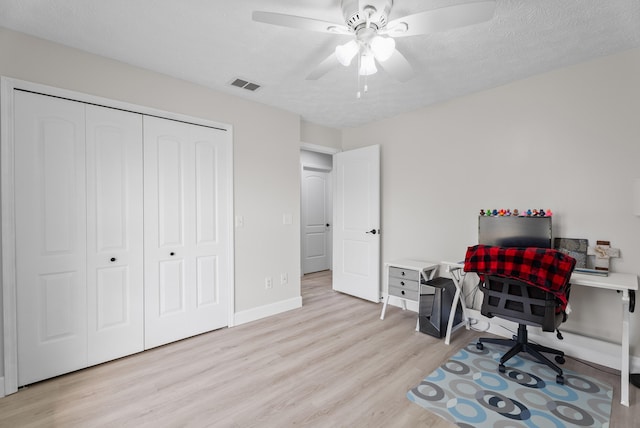 office space with baseboards, visible vents, ceiling fan, light wood-style floors, and a textured ceiling