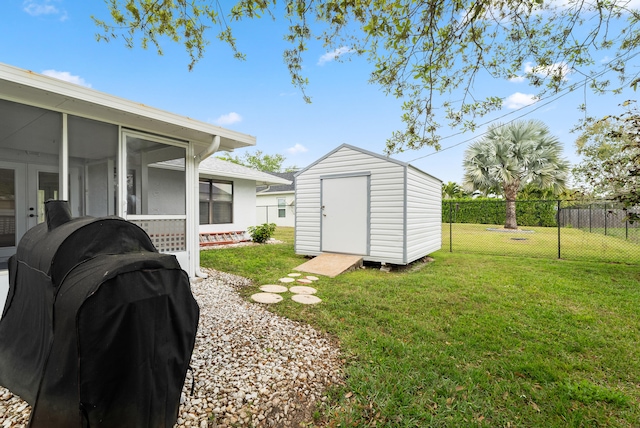 view of yard with an outbuilding, a storage unit, fence private yard, and a sunroom