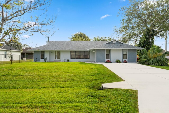 ranch-style home featuring a front lawn, concrete driveway, and fence