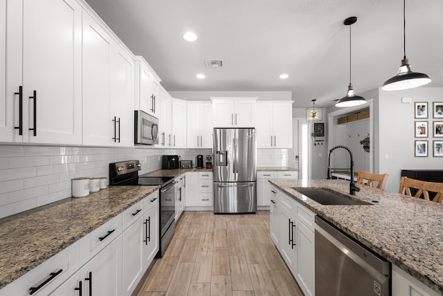 kitchen featuring tasteful backsplash, visible vents, appliances with stainless steel finishes, white cabinetry, and a sink