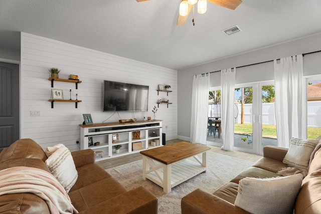 living room featuring visible vents, light wood-type flooring, and ceiling fan