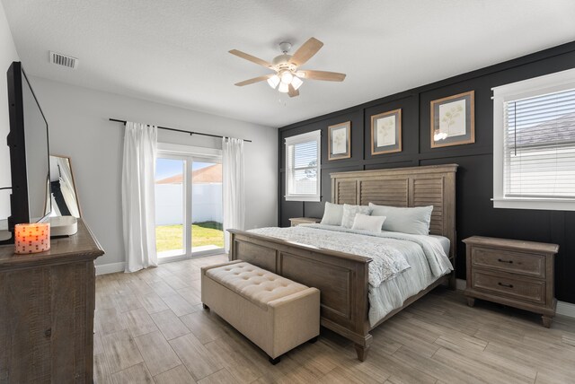 bedroom featuring access to exterior, visible vents, baseboards, ceiling fan, and light wood-type flooring