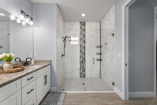 bathroom featuring a marble finish shower, vanity, and wood finished floors