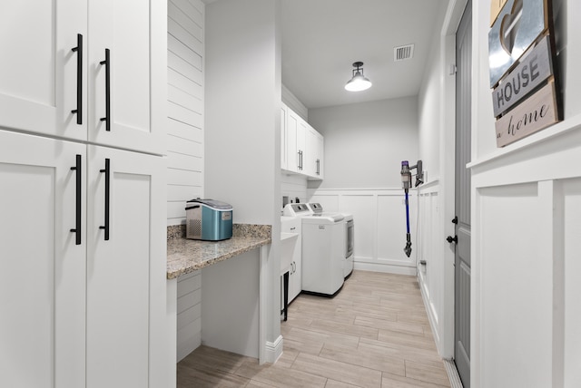 laundry room with visible vents, wood tiled floor, separate washer and dryer, cabinet space, and wainscoting