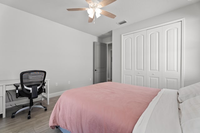 bedroom with visible vents, a ceiling fan, a closet, light wood-style floors, and baseboards