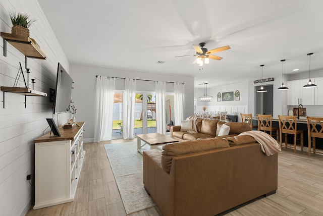 living area featuring light wood-style flooring and a ceiling fan