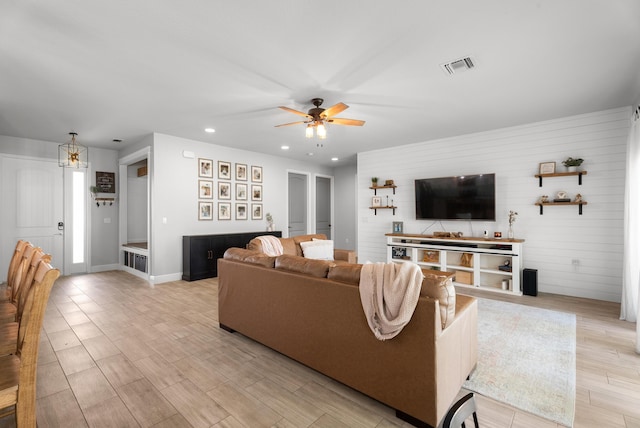 living area with light wood-type flooring, visible vents, ceiling fan with notable chandelier, recessed lighting, and baseboards