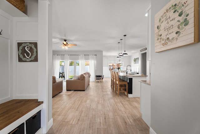 living area with ceiling fan and light wood finished floors