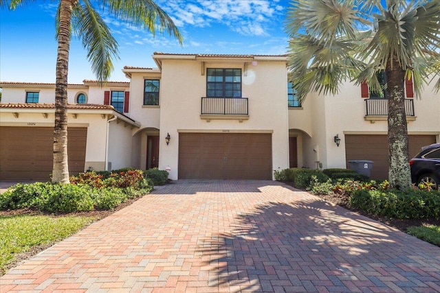 mediterranean / spanish-style home with an attached garage, decorative driveway, and stucco siding