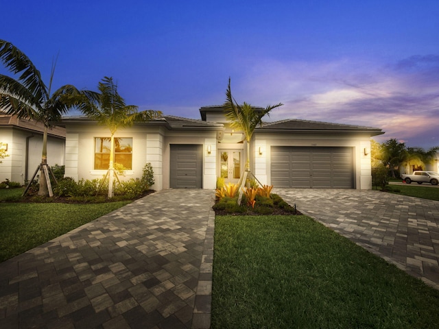 view of front of property with a garage, decorative driveway, and a front yard