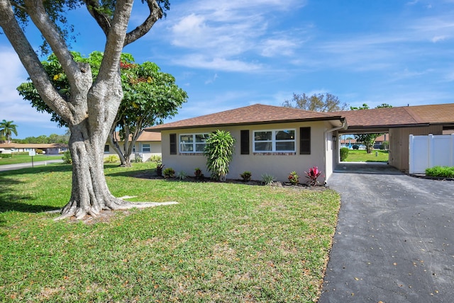 ranch-style house with a front lawn, an attached carport, and stucco siding