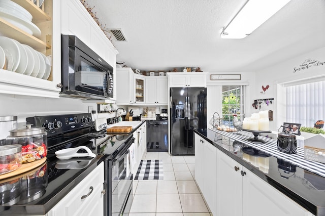 kitchen with white cabinets, dark countertops, black appliances, a sink, and light tile patterned flooring