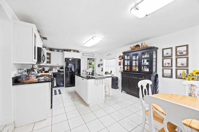 kitchen featuring black fridge with ice dispenser, white cabinets, dark countertops, a kitchen bar, and glass insert cabinets