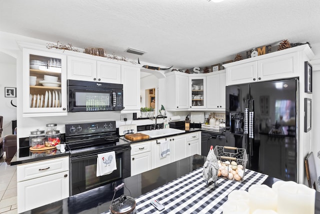 kitchen featuring dark countertops, black appliances, tile patterned flooring, and a sink