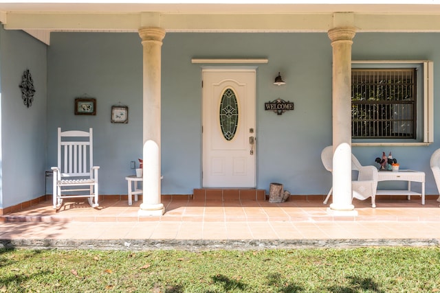 doorway to property featuring a porch and stucco siding