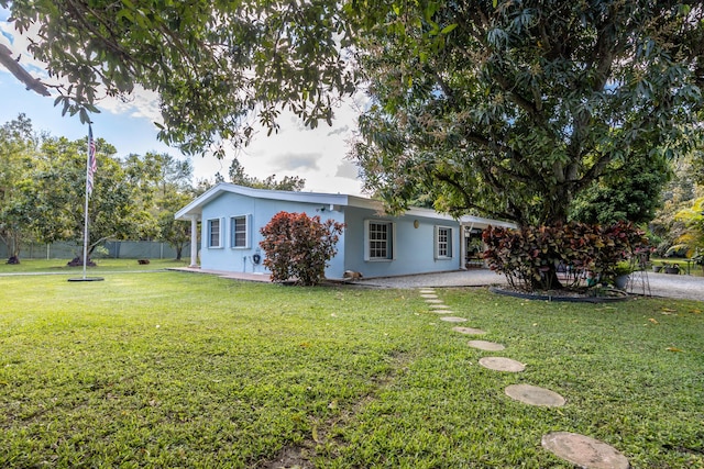 view of front facade with fence, a front lawn, a patio, and stucco siding