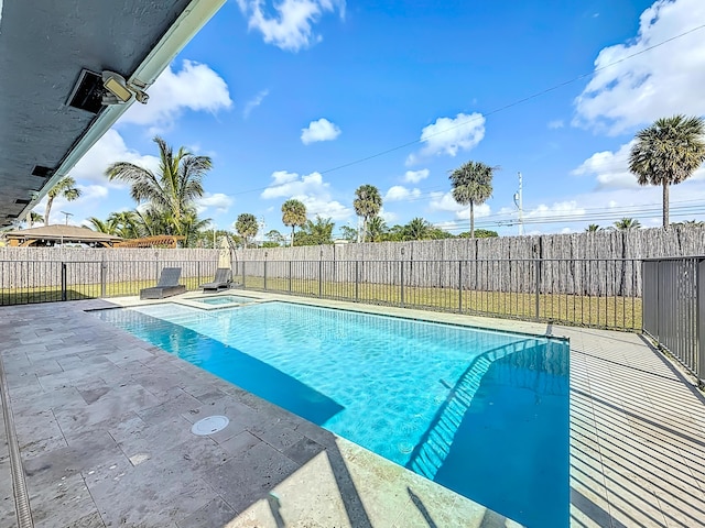 view of pool featuring a patio area, a fenced backyard, and a pool with connected hot tub