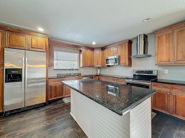 kitchen featuring wall chimney exhaust hood, appliances with stainless steel finishes, and brown cabinets