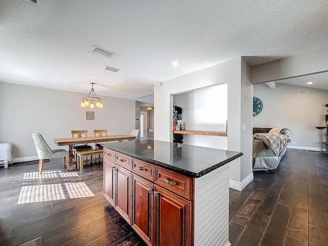 kitchen featuring dark wood-style floors, pendant lighting, a kitchen island, and a textured ceiling