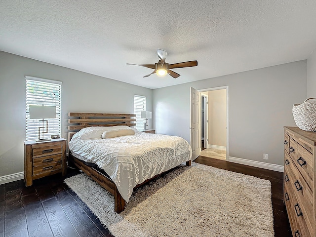 bedroom featuring dark wood-type flooring, multiple windows, baseboards, and a ceiling fan