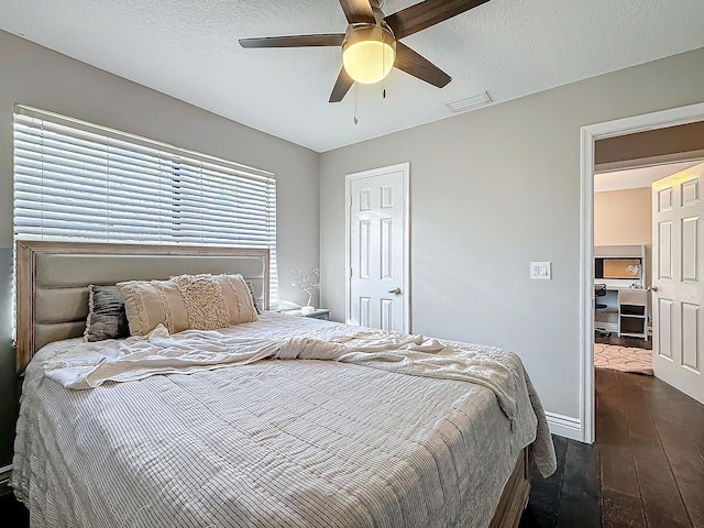 bedroom with baseboards, visible vents, a ceiling fan, dark wood finished floors, and a textured ceiling