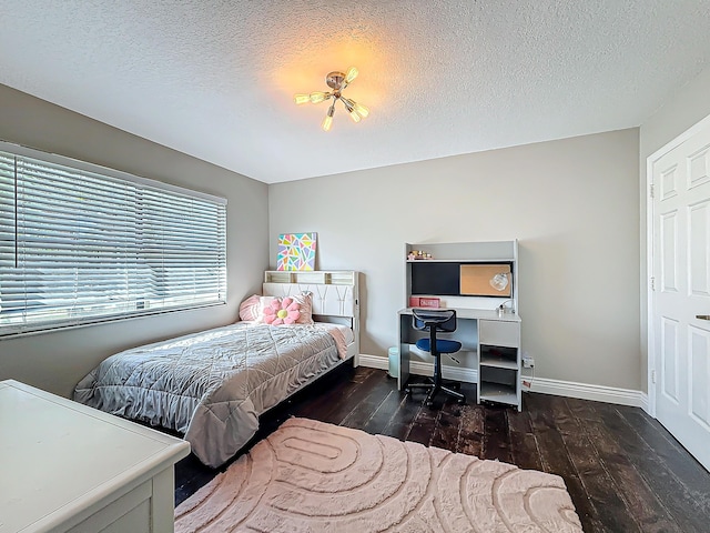 bedroom featuring a textured ceiling, hardwood / wood-style flooring, and baseboards