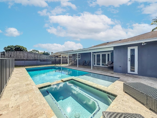 view of swimming pool featuring a fenced backyard, a pool with connected hot tub, a patio, and french doors