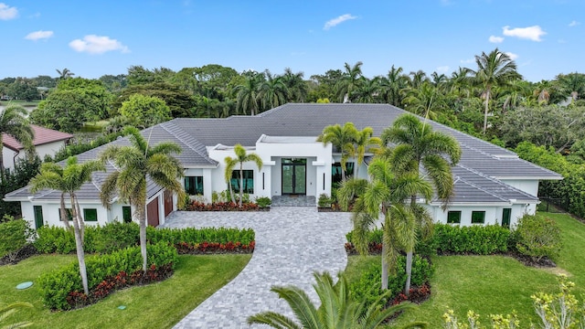 view of front of home with a tile roof, a front lawn, decorative driveway, and stucco siding