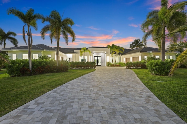 view of front of house with an attached garage, a front lawn, decorative driveway, and stucco siding