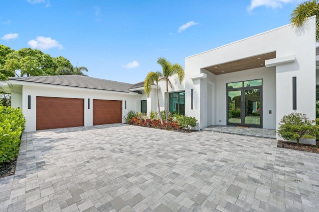 view of front of house with a garage, decorative driveway, and stucco siding