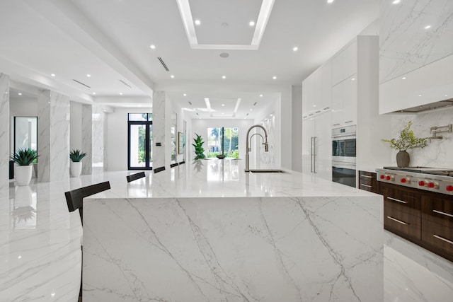 kitchen featuring modern cabinets, white cabinetry, stainless steel appliances, and a sink