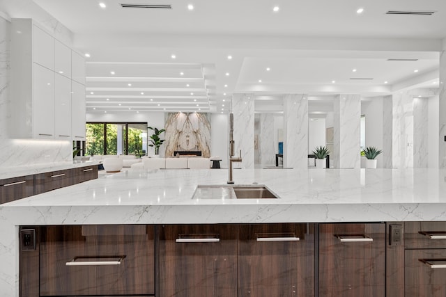 kitchen featuring white cabinets, modern cabinets, open floor plan, a sink, and recessed lighting