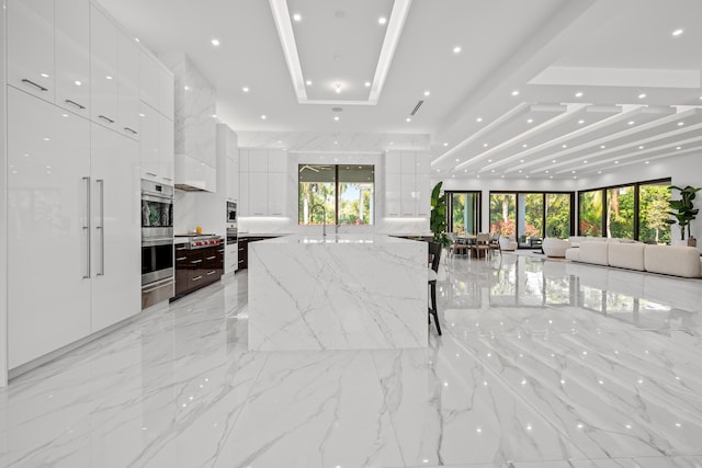 kitchen featuring open floor plan, marble finish floor, modern cabinets, and white cabinetry